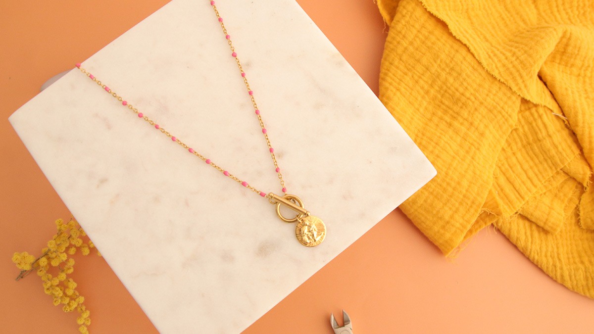Collier acier inoxydable doré, perles résine fuchsia et breloque signe astro